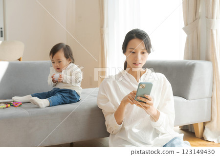 Mom looking at smartphone and girl playing with toys 123149430