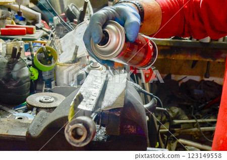 Mechanic Using Spray Lubricant on Metal Clamp Workshop Maintenance Mechanic Using Spray Lubricant on Metal Clamp Workshop Maintenance 123149558