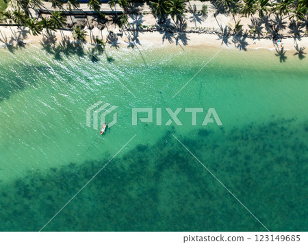 Emerald green water with visible seabed and a small fishing boat near the shore, lined with palm tree shadows. Koh Samui, Thailand. 123149685