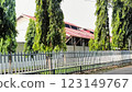 Greenery enhances this tranquil area with tall trees by a fence near a house, providing a peaceful suburban aesthetic surrounded by nature. 123149767