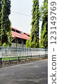 Greenery enhances this tranquil area with tall trees by a fence near a house, providing a peaceful suburban aesthetic surrounded by nature. 123149769
