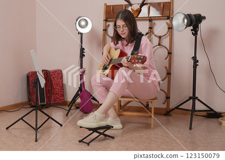 Woman guitarist expression playing classical six string acoustic guitar in strumming style in studio Woman guitarist expression playing classical six string acoustic guitar in strumming style in studio 123150079