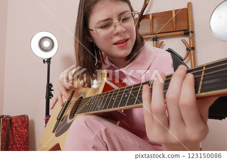 Young woman playing classical six string acoustic guitar and singing song and shaking head to beat Young woman playing classical six string acoustic guitar and singing song and shaking head to beat 123150086