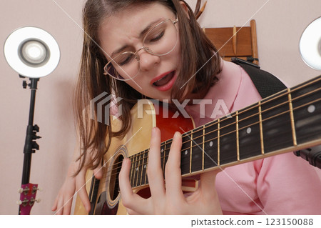 Close-up of woman guitarist playing acoustic guitar, singing song as she plucks strings with emotion 123150088