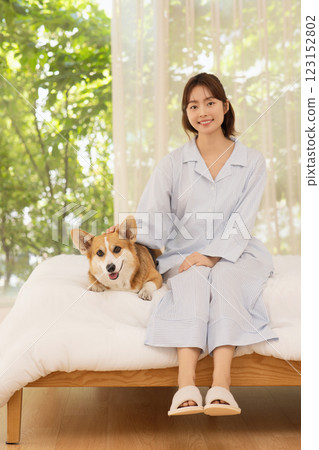 Side view of woman sitting on bed with dog 123152802