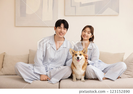 A young couple sitting on a sofa and resting with their dog 123152890