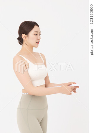 Cropped view of young woman measuring waist circumference wearing sportswear 123153000