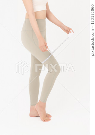 Cropped view of young woman wearing sportswear measuring leg circumference Cropped view of young woman wearing sportswear measuring leg circumference 123153060