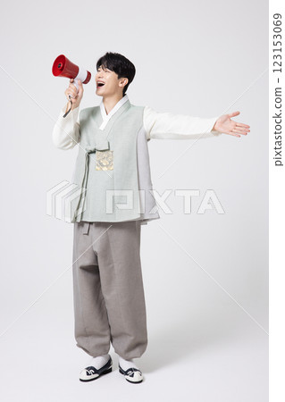 A young man wearing a hanbok and shouting while holding a megaphone 123153069
