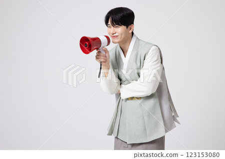 A young man wearing a hanbok and shouting while holding a megaphone 123153080