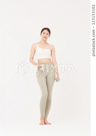 Cropped view of young woman wearing sportswear measuring leg circumference 123153102