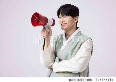 A young man wearing a hanbok and shouting while holding a megaphone 123153115