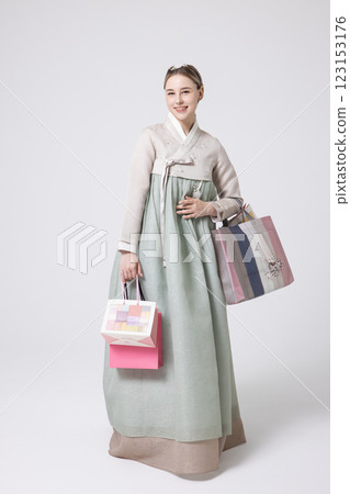 A Western woman standing wearing a Hanbok and holding shopping bags 123153176