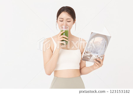 Portrait of young woman wearing sportswear, drinking healthy drink and reading book 123153182