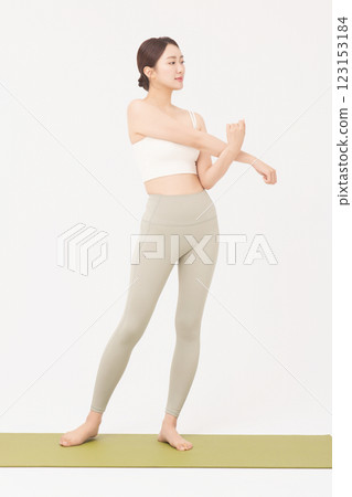 Portrait of a young woman wearing sportswear and stretching on a yoga mat Portrait of a young woman wearing sportswear and stretching on a yoga mat 123153184