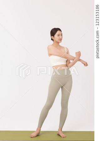 Portrait of a young woman wearing sportswear and stretching on a yoga mat Portrait of a young woman wearing sportswear and stretching on a yoga mat 123153186