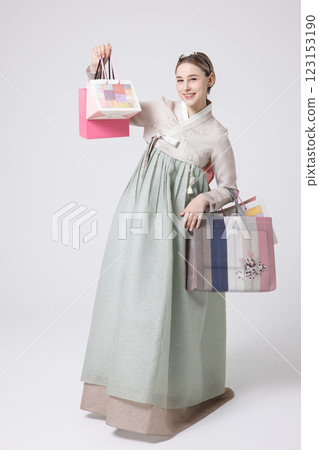 A Western woman standing wearing a Hanbok and holding shopping bags A Western woman standing wearing a Hanbok and holding shopping bags 123153190