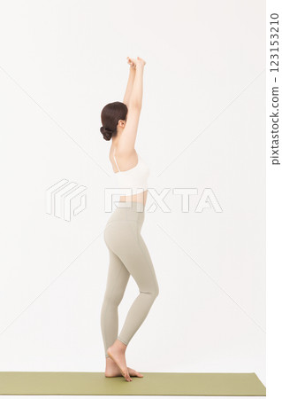 Portrait of a young woman wearing sportswear and stretching on a yoga mat 123153210