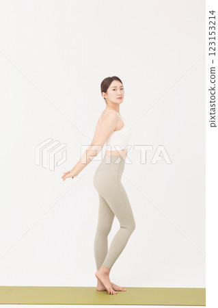 Portrait of a young woman wearing sportswear and stretching on a yoga mat Portrait of a young woman wearing sportswear and stretching on a yoga mat 123153214