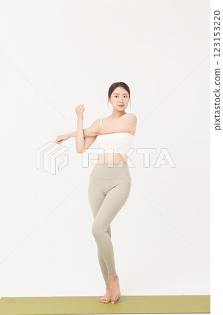 Portrait of a young woman wearing sportswear and stretching on a yoga mat 123153220