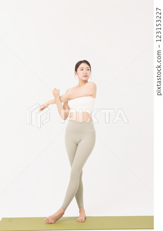 Portrait of a young woman wearing sportswear and stretching on a yoga mat Portrait of a young woman wearing sportswear and stretching on a yoga mat 123153227