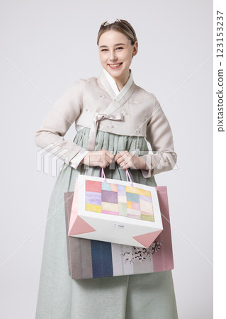 A Western woman standing wearing a Hanbok and holding shopping bags A Western woman standing wearing a Hanbok and holding shopping bags 123153237