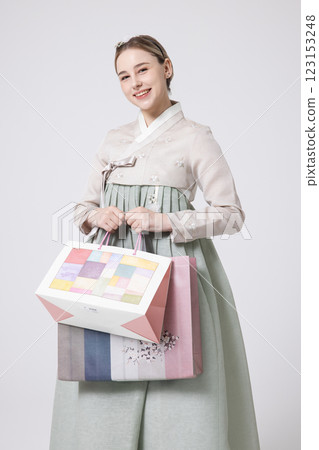 A Western woman standing wearing a Hanbok and holding shopping bags A Western woman standing wearing a Hanbok and holding shopping bags 123153248