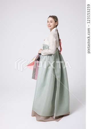 A Western woman standing wearing a Hanbok and holding shopping bags 123153259