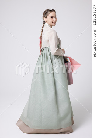 A Western woman standing wearing a Hanbok and holding shopping bags 123153277