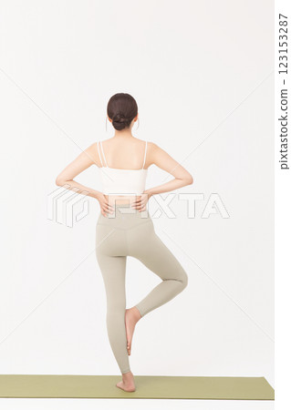 Portrait of a young woman wearing sportswear and stretching on a yoga mat Portrait of a young woman wearing sportswear and stretching on a yoga mat 123153287