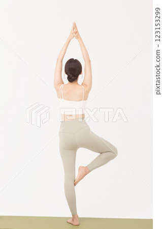 Portrait of a young woman wearing sportswear and stretching on a yoga mat 123153299