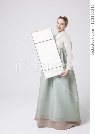 A Western woman standing wearing a Hanbok and holding a hanging scroll A Western woman standing wearing a Hanbok and holding a hanging scroll 123153315
