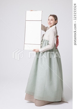 A Western woman standing wearing a Hanbok and holding a hanging scroll A Western woman standing wearing a Hanbok and holding a hanging scroll 123153324