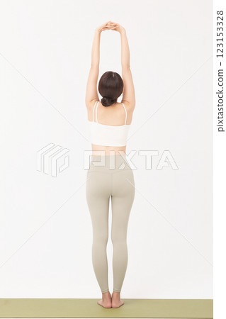 Portrait of a young woman wearing sportswear and stretching on a yoga mat 123153328