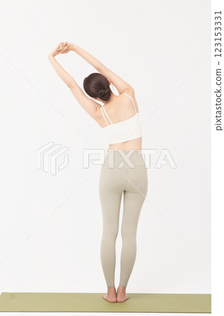 Portrait of a young woman wearing sportswear and stretching on a yoga mat Portrait of a young woman wearing sportswear and stretching on a yoga mat 123153331