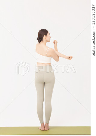 Portrait of a young woman wearing sportswear and stretching on a yoga mat Portrait of a young woman wearing sportswear and stretching on a yoga mat 123153337