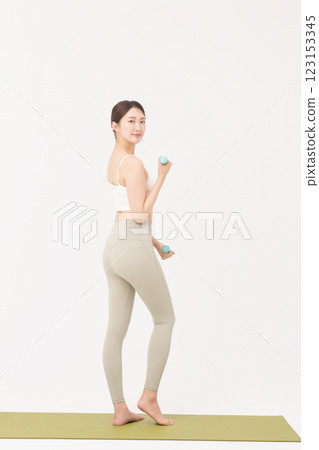 Portrait of a young woman doing bodyweight exercises while holding dumbbells 123153345