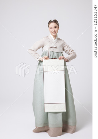 A Western woman standing wearing a Hanbok and holding a hanging scroll A Western woman standing wearing a Hanbok and holding a hanging scroll 123153347
