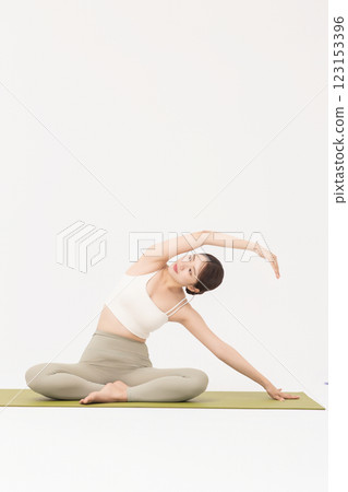 Portrait of a young woman wearing sportswear sitting on a yoga mat and stretching Portrait of a young woman wearing sportswear sitting on a yoga mat and stretching 123153396