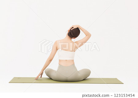 Portrait of a young woman wearing sportswear sitting on a yoga mat and stretching 123153454