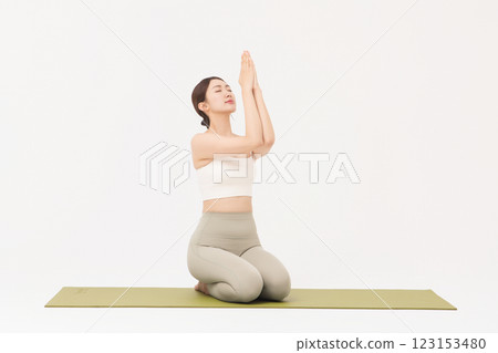Portrait of a young woman wearing sportswear sitting on a yoga mat and stretching 123153480