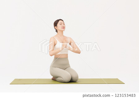 Portrait of a young woman wearing sportswear sitting on a yoga mat and stretching Portrait of a young woman wearing sportswear sitting on a yoga mat and stretching 123153483