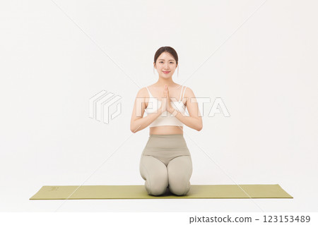 Portrait of a young woman wearing sportswear sitting on a yoga mat and stretching Portrait of a young woman wearing sportswear sitting on a yoga mat and stretching 123153489
