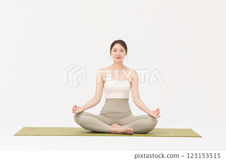 Portrait of a young woman wearing sportswear sitting on a yoga mat and stretching Portrait of a young woman wearing sportswear sitting on a yoga mat and stretching 123153515