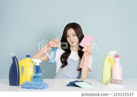 A 22-year-old woman sitting in front of a table, wearing rubber gloves and holding a cleaning tool 123153537