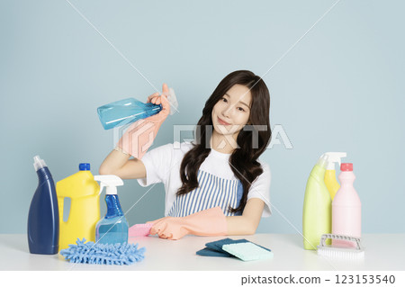 A 23-year-old woman sitting in front of a table, wearing rubber gloves and holding a cleaning tool 123153540