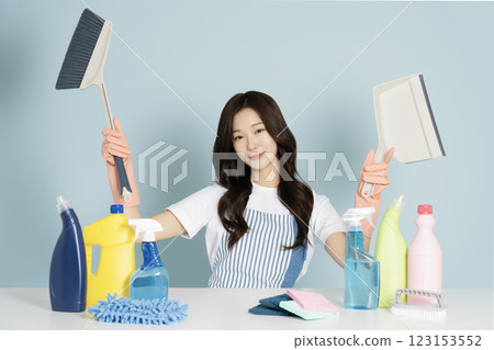 A 26-year-old woman sitting in front of a table, wearing rubber gloves and holding a cleaning tool 123153552