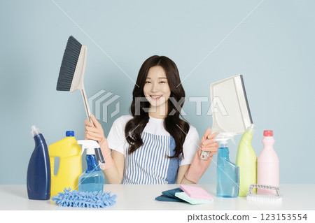 A 27-year-old woman sitting in front of a table, wearing rubber gloves and holding a cleaning tool A 27-year-old woman sitting in front of a table, wearing rubber gloves and holding a cleaning tool 123153554