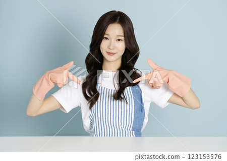 A woman in her 20s sitting in front of a table wearing rubber gloves A woman in her 20s sitting in front of a table wearing rubber gloves 123153576