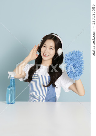 A woman in her 20s wearing a headset and holding detergent and a mop for cleaning A woman in her 20s wearing a headset and holding detergent and a mop for cleaning 123153599